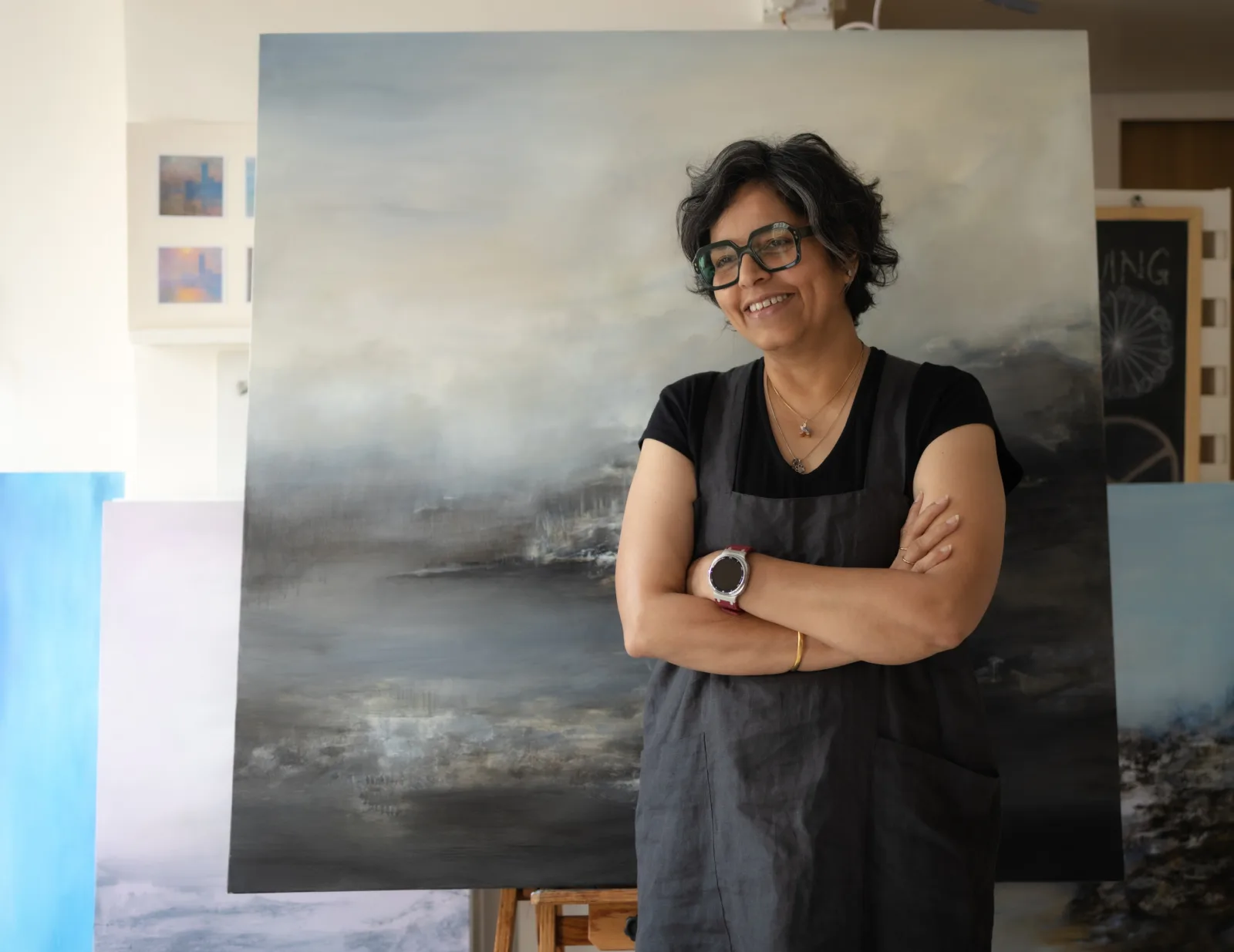 Reena Yadav Ramakrishnan in her studio, before a large landscape painting